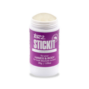 Open purple supplement bottle with a beige powder scoop resting at the top opening; white cap visible and partial label text shows on the bottle.