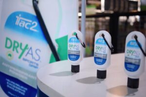 Close-up of white DRYAS antiperspirant spray bottles on a display counter with a blurred background.